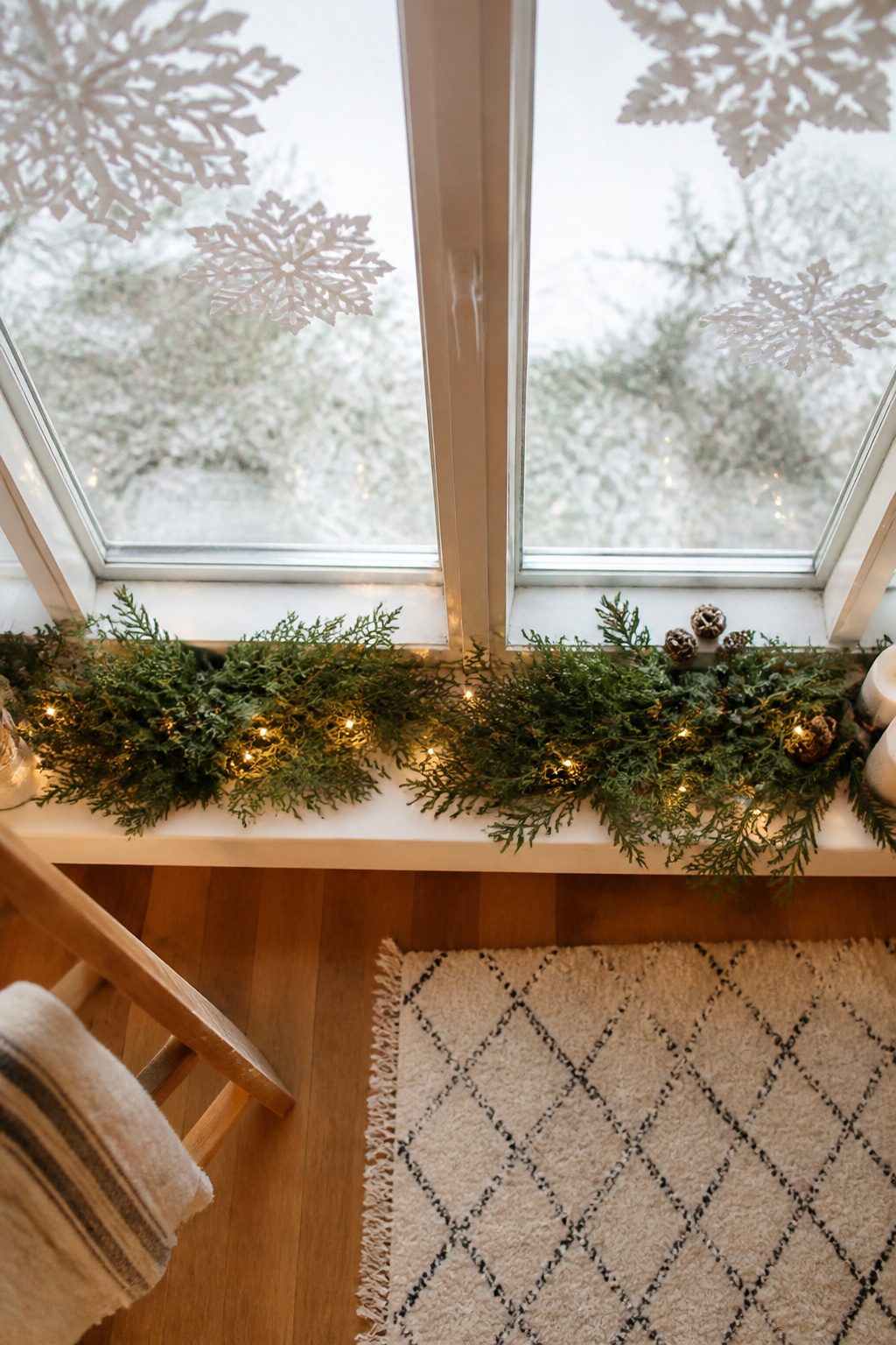 Paper snowflakes hanging from a window sill, made from various types of paper.